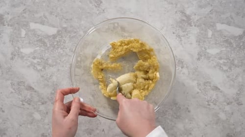 Smashing Riped Bananas in a Glass Mixing Bowl to Prepare Coconut Banana Pancakes