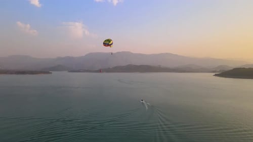 Man enjoying a para sailing flight at beach during sunset with beautiful view, drone shot