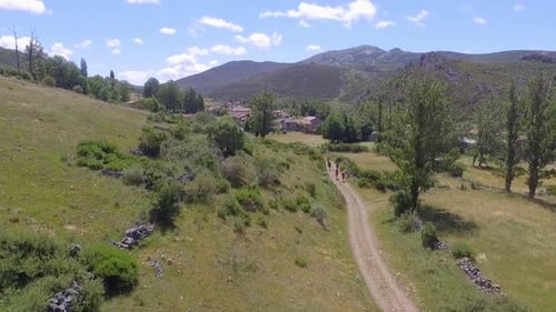 People Walking on Dirt Road in Rural Landscape