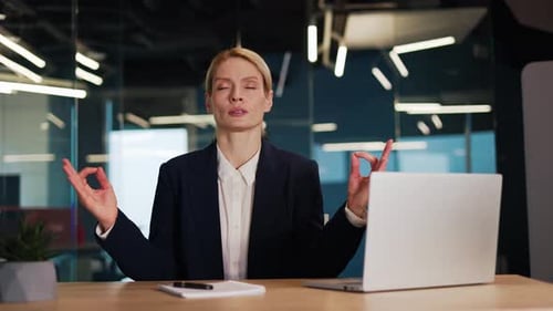 Concentrated Relaxed Businesswoman Meditating or Doing Yoga in Office