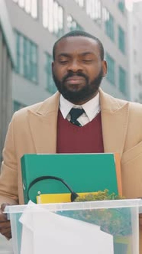 Um homem está do lado de fora de um prédio de escritórios enquanto segura documentos importantes nas mãos