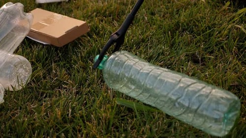 Closeup of a Garbage Collection Tongs with a Plastic Bottle in the City