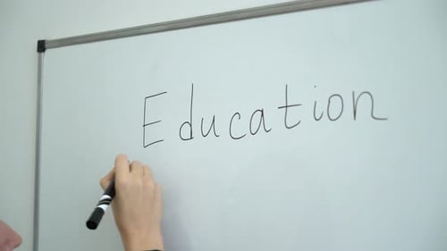 maestra de primer plano escribiendo a mano en una pizarra blanca o pizarra en el aula