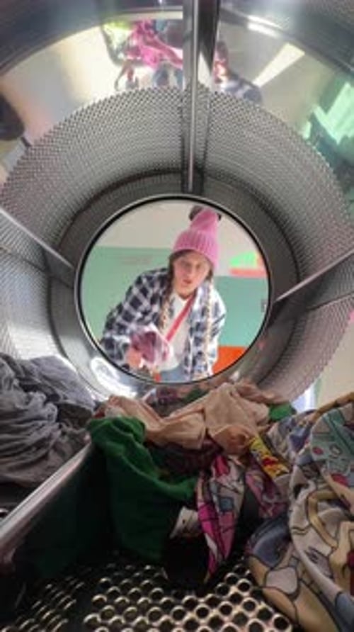 Young Adult Puts Clothes in Washing Machine