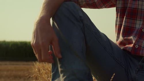 Man Leg Straw Bale in Sunlight Closeup. Field Worker Resting on Hay