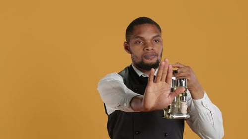 Waiter in Uniform Showing a Stop Sign with His Palm Raised in Studio