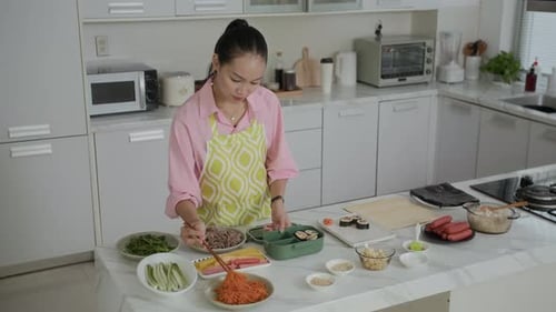 Asian Housewife Putting Self-made Kimbap in Lunch Box at Kitchen