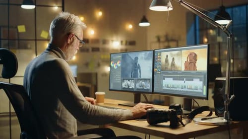 Evening in Creative Office: Professional Middle Aged Videographer Works on Desktop Computer, Doing