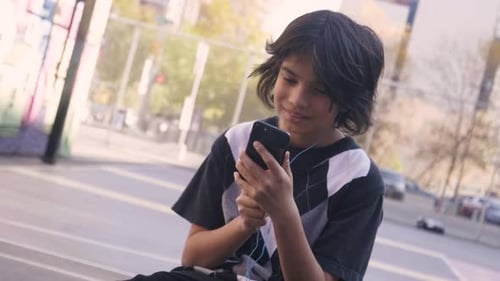 Smiling Preteen Boy Using Smart Phone On Urban Basketball Court Slow Motion