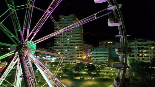 Illuminated Ferris Wheel at Night in an Urban Setting