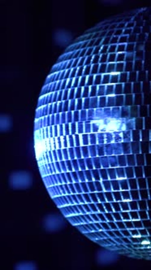 Disco ball spins and reflects colorful lights. Vertical