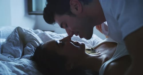 Filmaufnahme eines verliebten jungen, frisch verheirateten Paares im Pyjama, das Spaß hat und sich auf dem