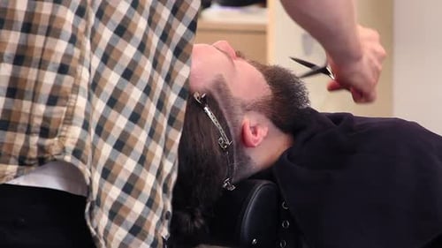 Close up of barber trimming customer's hipster beard with shears
