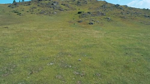 Aerial Along the Green Rocky Hill Drone Flies Over the Hill and Reveal the View of a Valley to with