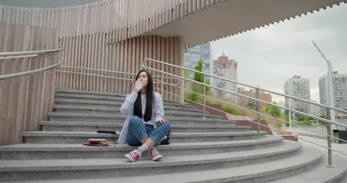 Young Woman Drinking Water Sitting on Urban Steps