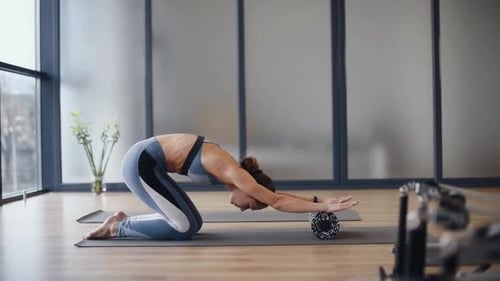 Woman Exercising with Foam Roller on Exercise Mat