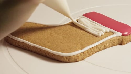 pastry chef decorates New Year's gingerbread cookies with colorful glaze, close-up.