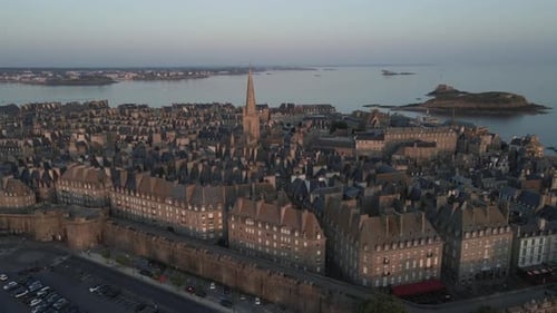 Saint-Malo old city with Cathedral bell tower at sunset, Brittany in France. Aerial forward tilt dow