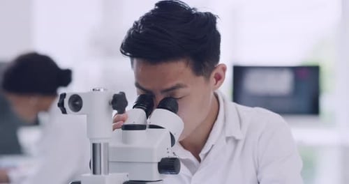 Young Adult Scientist Using Microscope in Bright Lab