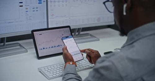 Man Analyzes Data on Smartphone in Office