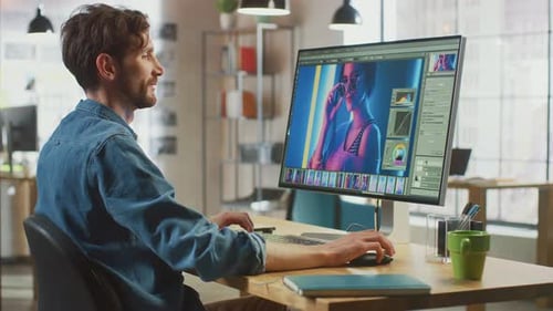 Male Digital Editor in Jeans Shirt Works in Image Editing Software on His Personal Computer with Bi