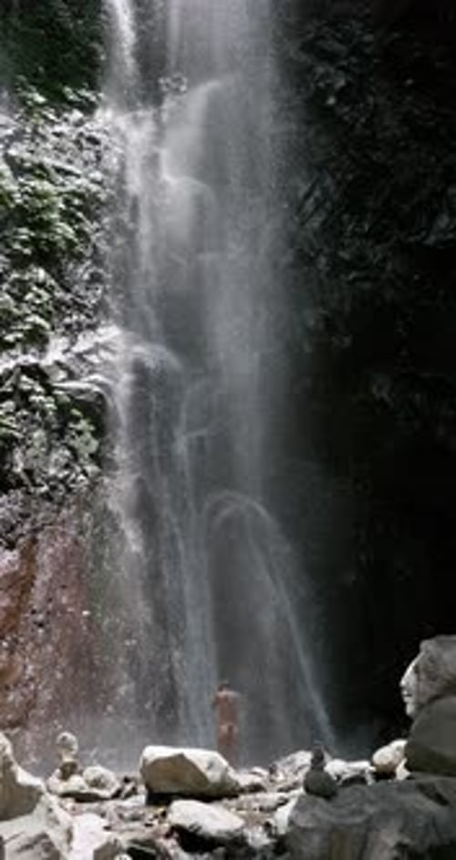 Woman Enjoying Tropical Waterfall in Beautiful Green Setting
