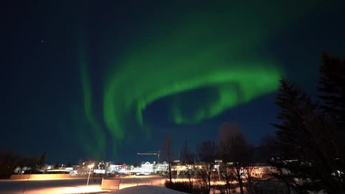 Magnificent green glowing aurora borealis lights up the sky in over the town of Selfoss in Iceland