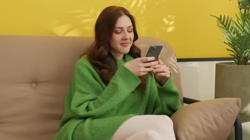 Woman Using Smartphone Relaxing at Home on Couch
