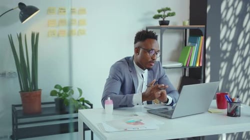 Smiling African American Man Office Worker Sitting at Table and Having Videochat on Laptop Computer