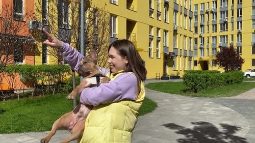 Young Woman Holding Dog Outside Apartment Building