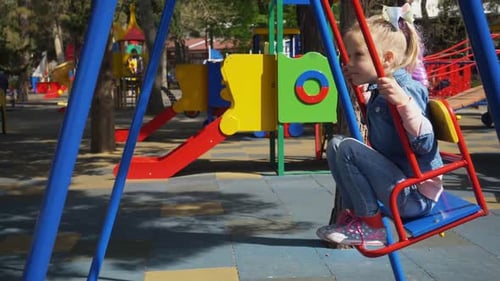 playgroung, childhood - little blonde girl at the playground on the swing