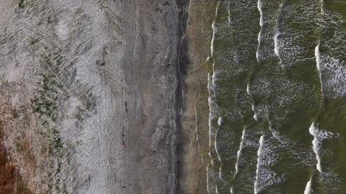 Aerial shot of coastline: brown dunes meet sandy beach