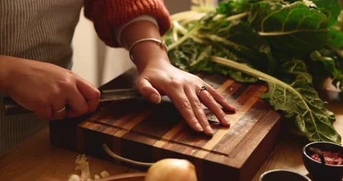 Woman Slicing Garlic on Cutting Board in Kitchen