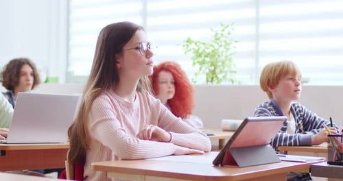 Cute Female Student in Eyeglasses with Long Brown Hair Raising Hand and Waiting for Turn to Answer