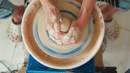 Une potière travaille sur un tour de potier et fabrique un pot en céramique en argile dans un atelier de poterie.