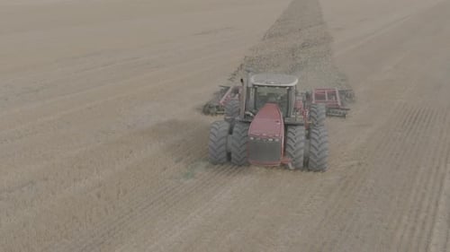 Big Red Tractor Pulling Disc Harrow Through Field in Preparation Soil for Planting New Crops