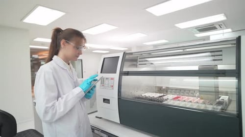 Scientist using automated medical testing equipment in laboratory