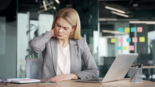 Woman at Desk Massaging Stiff Neck in Office