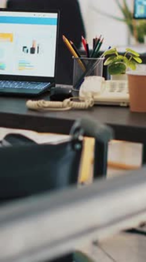 Vertical Video Wheelchair in Office and Laptop on Desk Showing Business Analytics