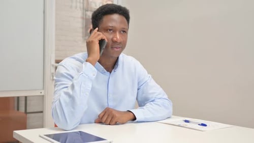 African Businessman Talking on phone in Office