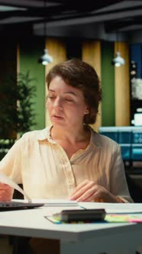 Woman Stretches Neck at Desk in Dark Office