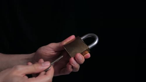 close up of hands opening a yellow padlock with key