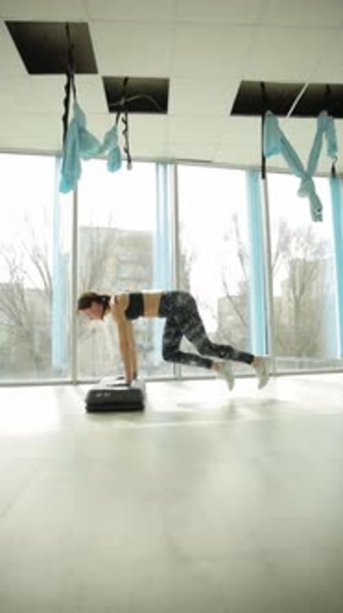 Woman Exercising on Step Platform in Gym