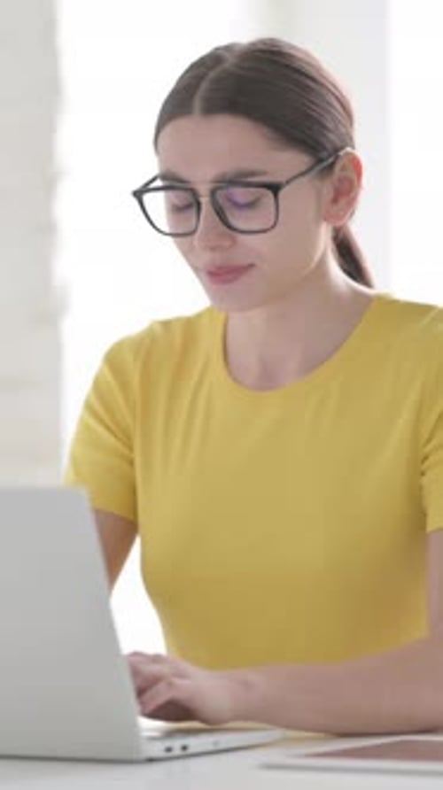 Frau fühlt sich gestresst, wenn sie den Laptop im Büro benutzt, vertikales Video