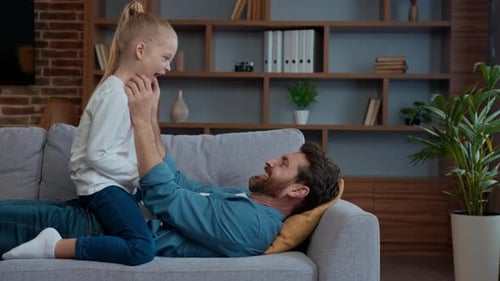 Father and Daughter Playfully Interacting on Couch Indoors