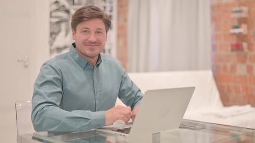 Man Using Laptop Gives Thumbs Up at Home