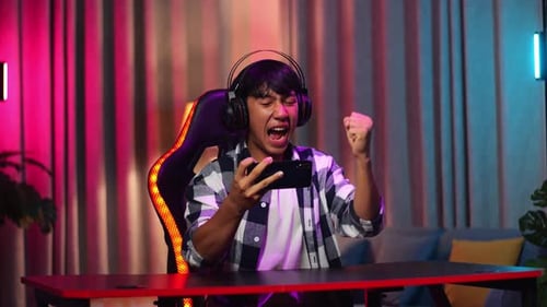 Young Man Playing Mobile Game and Celebrating Victory