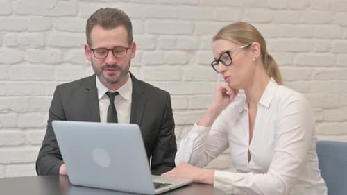 Business Professionals Discuss Laptop in Bright Office