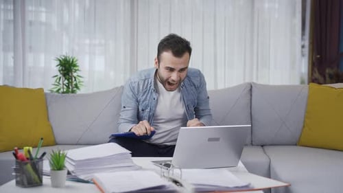 Man Cheering While Using Laptop at Home
