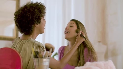 Two Smiling Women Applying Makeup Indoors